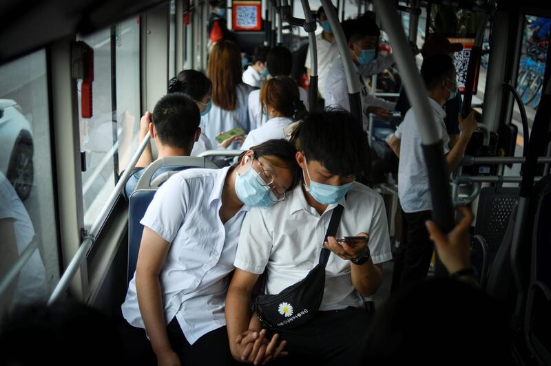 A couple wearing face mask ride on a bus during rush hour in Beijing. China reported 12 new cases of Covid-19 on June 24, including seven domestic cases in Beijing.   AFP