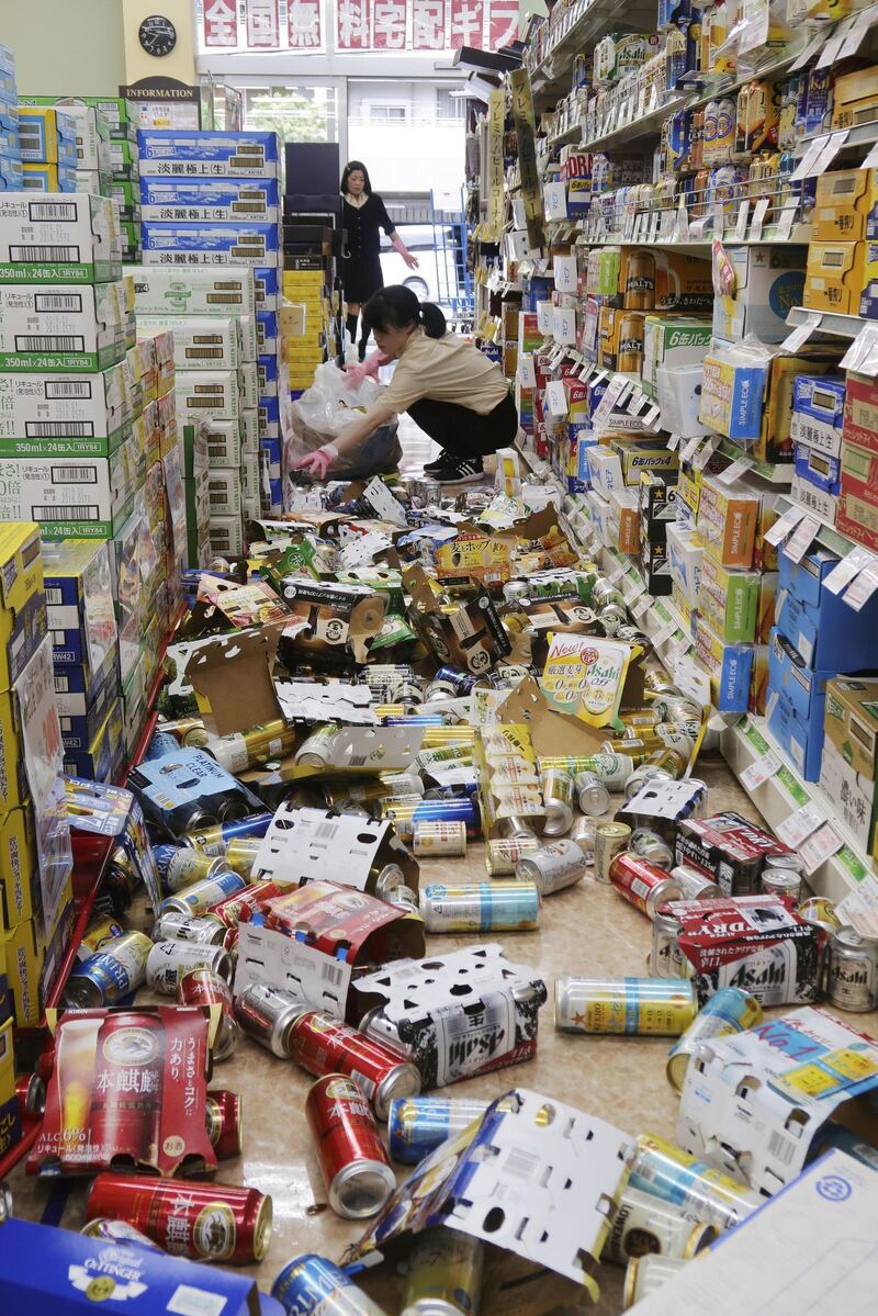 Employees try to remove bottles and cans of beverages which are scattered by an earthquake at a liquor shop in Hirakata, Osaka. Reuters