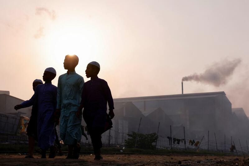 Children walk past as smoke rises from a re-rolling mill in Dhaka, Bangladesh. Reuters