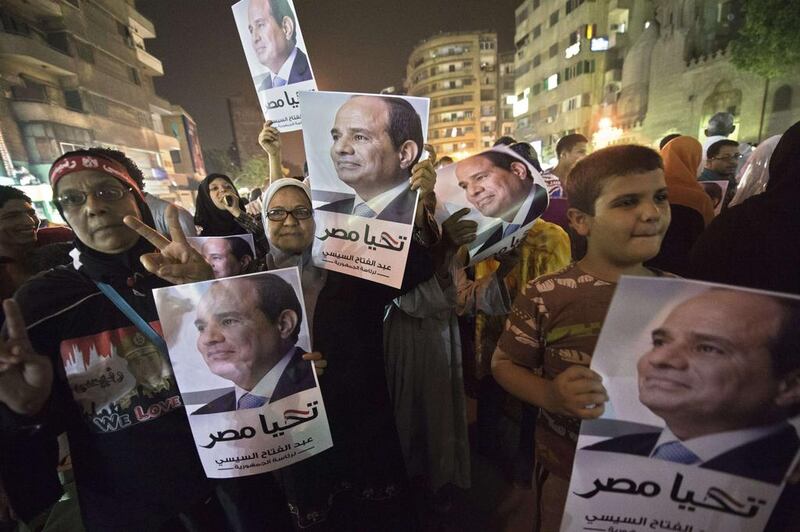 Supporters of Egypt's former army chief Abdel Fattah El Sisi hold his portraits as they watch him on a screen in central Cairo on May 5, 2014, during his first television interview since announcing he would run for president. AFP Photo


