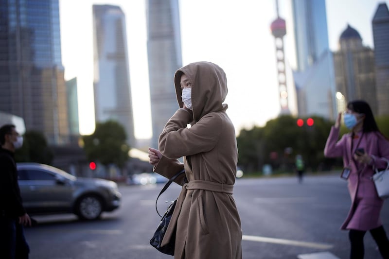 People wear protective face masks, following an outbreak of the novel coronavirus disease (COVID-19), at Lujiazui financial district in Shanghai, China March 19, 2020. REUTERS/Aly Song