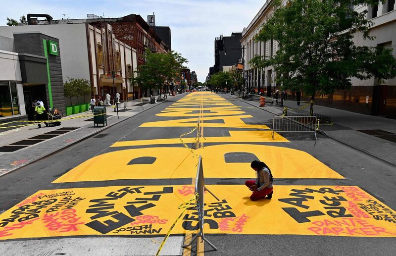 A person takes a knee on a giant "Black Lives Matter" mural painted on Fulton Street on June 15, 2020 in the Brooklyn Borough of New York City.  AFP