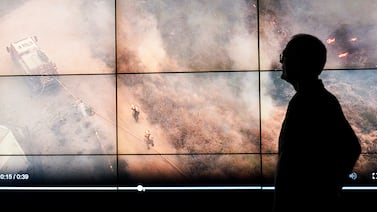 Screens show firefighters battling a wildfire in the US. AP