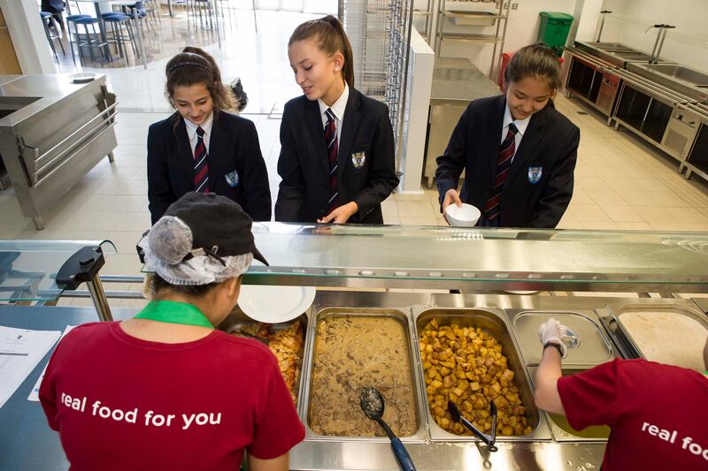 ABU DHABI, UNITED ARAB EMIRATES, SEPTEMBER 24, 2014. Slices prepares fresh, healthy, home cooked style meals with nutrional value on site for Schools in the UAE. LtoR: Dara Hussein (yr 10, English/Egyptian), Zoe Claudel (yr 10, French) and 
Aliya Davletova (yr10 Kazakhstan) students at Brighton College in Al Ain wait in lin eto have their lunch served at the Slices cafeteria. (Photo: Antonie Robertson/The National) Journalist: Dana Moukhallati. Section: National.