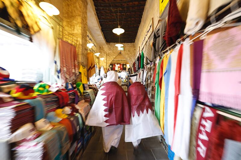 Qatari youths wearing their national flags walk in Souq Waqif marketplace in Doha. AFP