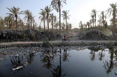 A motorcyclist rides along side the garbage floating on water canal running from the Euphrates River in Karbala, Iraq September 23, 2020. Picture taken September 23, 2020. REUTERS/Abdullah Dhiaa Al-Deen