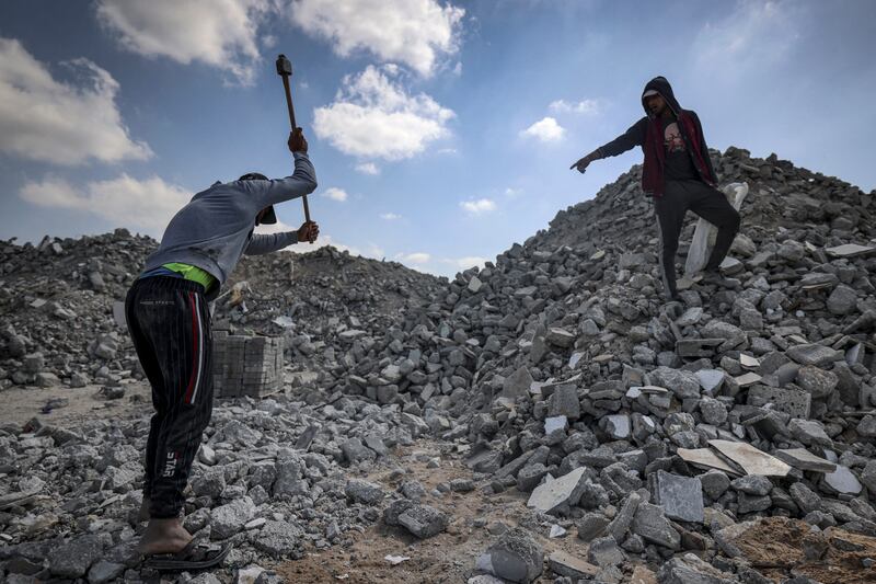 Workmen break rubble into pieces as they recycle salvaged construction materials from buildings destroyed during the May 2021 conflict between Hamas and Israel, at a rubble collection area in Gaza City's eastern suburb of Shujaiya. AFP