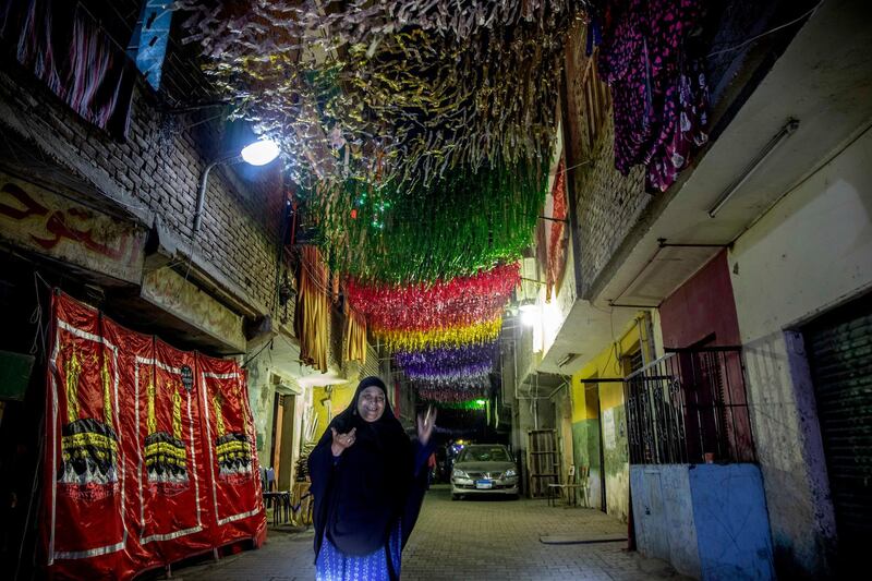 A woman walks on a street under decorations a day ahead of the holy month of Ramadan, in the Imbaba neighborhood of Giza, April 23, 2020. Muslims around the world are trying to maintain the cherished rituals of Islam holiest month during the coronavirus pandemic. (AP Photo/Nariman El-Mofty)