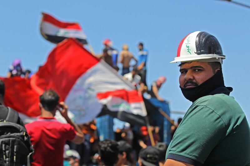 An Iraqi protester looks on as others wave national flags during an anti-government demonstration on Al Jumhuriyah bridge in the capital Baghdad.  AFP