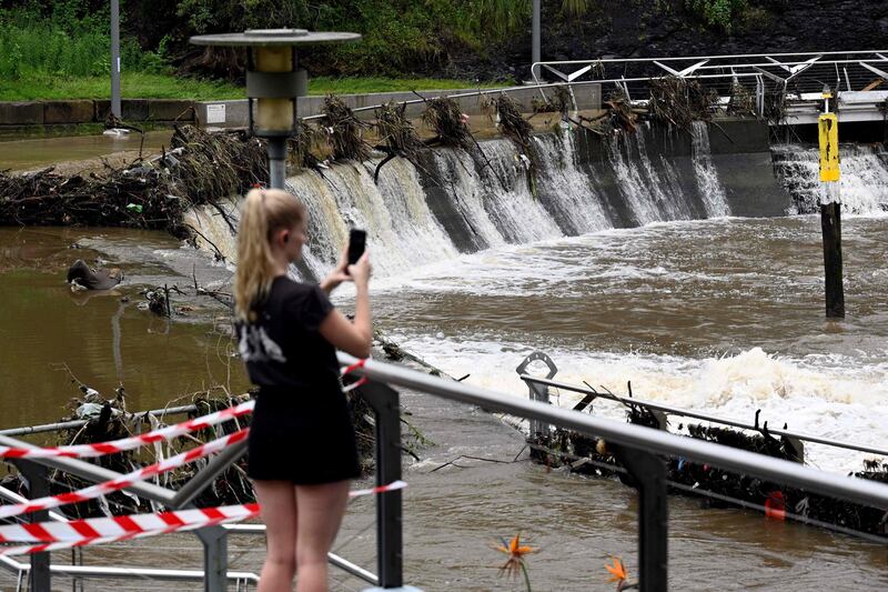 A woman takes pictures of the overflowing Parramatta river in Sydney. AFP