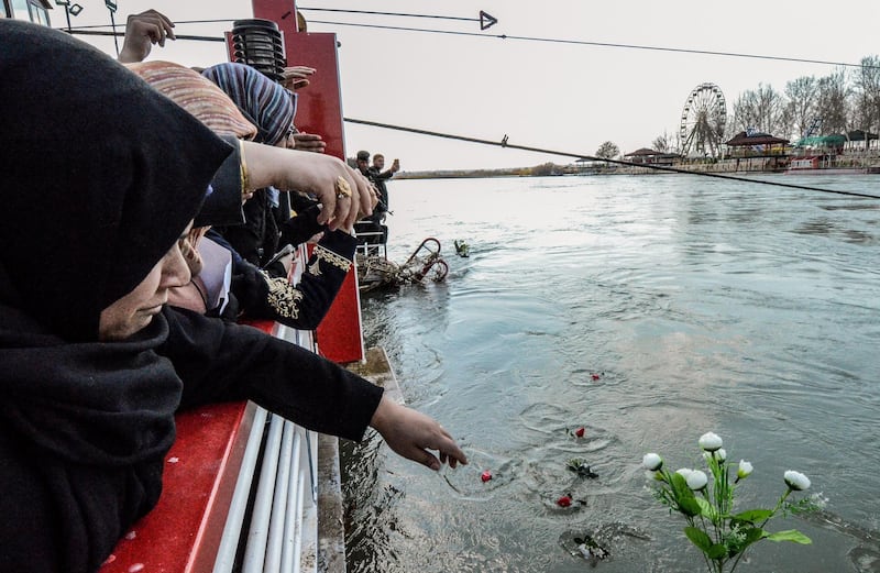 Iraqi women cast flowers into the Tigris river in remembrance for the victims of the capsized ferry in the northern Iraqi city of Mosul on March 22, 2019, following the incident which left at least 100 people dead, as the ferry was packed with families celebrating Kurdish New Year.    / AFP / Zaid AL-OBEIDI
