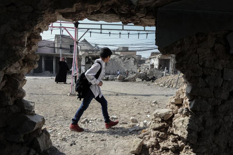 An Iraqi child walks with his school bag on the shoulder on the first day of school in Mosul.  AFP
