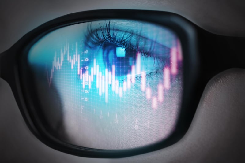 The reflection of the stock graph on a young adult women's glasses. Getty Images