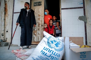 Members of a Palestinian family, some clad in mask due to the COVID-19 coronavirus pandemic, stand through the door of their home as they receive food aid provided by the United Nations Relief and Works Agency for Palestine Refugees (UNRWA) in Gaza City on September 15, 2020. (Photo by MOHAMMED ABED / AFP)
