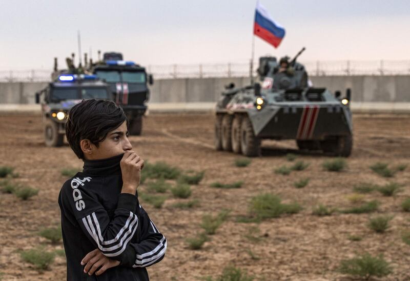 A young boy stands in front of Russian military vehicles on patrol with Turkish forces in the countryside of the town of Darbasiyah in Syria's northeastern Hasakeh province on the border with Turkey. AFP