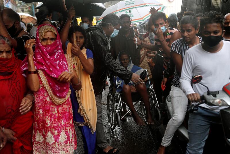 People make way for a man on a wheelchair to pass during an evacuation of a slum on the outskirts of Mumbai, India. Reuters