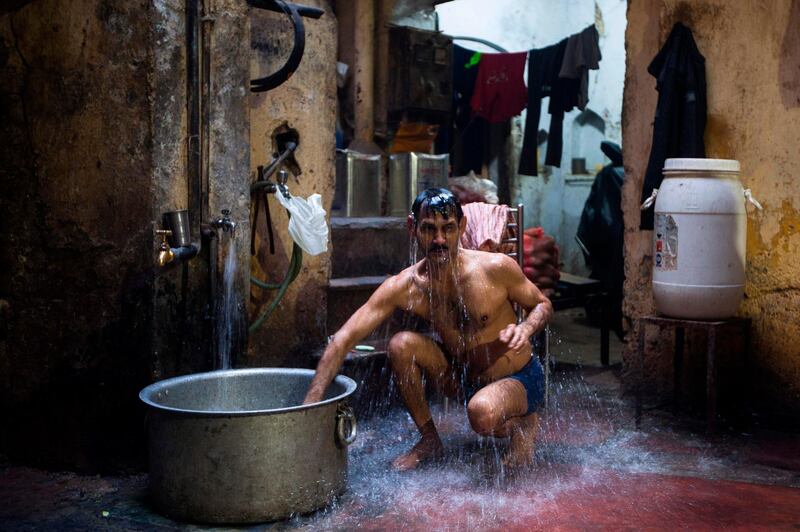 An Indian man bathes inside a workshop in the old quarters of New Delhi. AFP