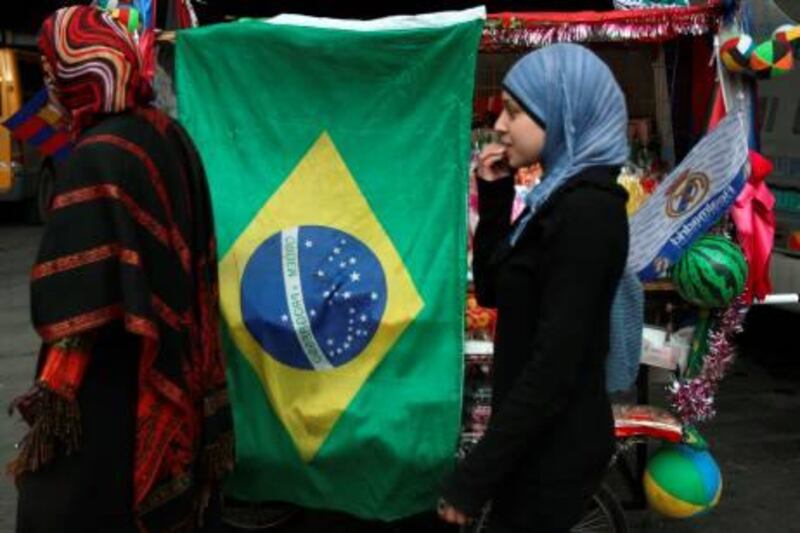 Palestinian women walk past a Brazilian flag hanging on a vendor’s cart in the centre of the West Bank city of Ramallah on December 7, 2010 a day after Argentina and Uruguay said they were joining Brazil in recognizing an independent Palestinian state, earning praise from Palestinian officials but an immediate sharp rebuke from Israel.  AFP PHOTO/ABBAS MOMANI
 *** Local Caption ***  826593-01-08.jpg