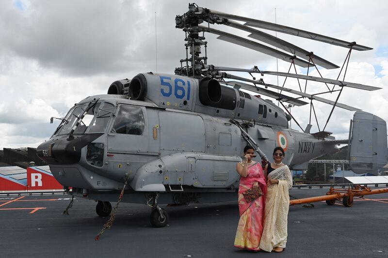 Women stand next to a Komoho Helicopter on the deck of the 'Vikrant'. AFP
