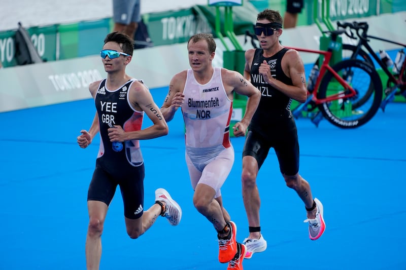 Alex Yee of Great Britain, Kristian Blummenfelt of Norway and Hayden Wilde of New Zealand run though the second transition.