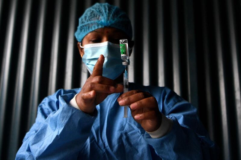 A health worker prepares to inoculate a woman with the Covid-19 coronavirus vaccine on the outskirts of Kathmandu on March 7, 2021. / AFP / Prakash MATHEMA
