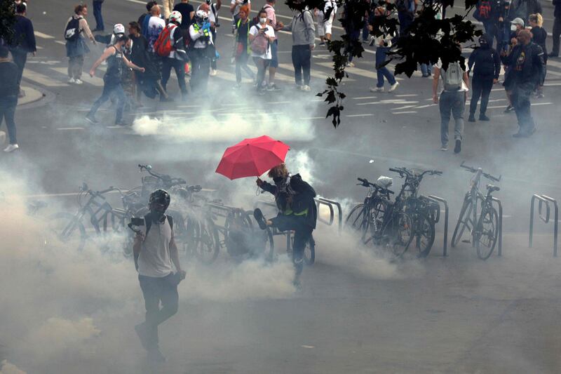 A demonstrator kicks away a smoking teargas shell during a national day of protest against compulsory Covid-19 vaccinations for certain workers and the compulsory use of health passes, in Paris.