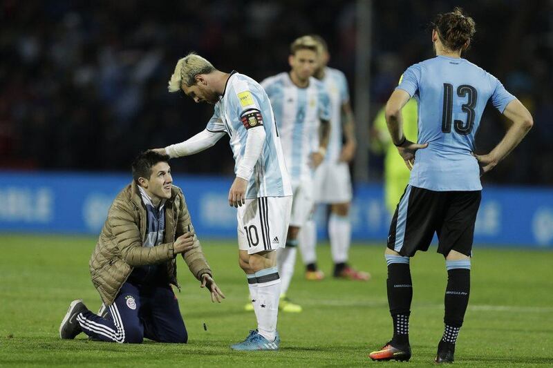 An Argentina fan who invaded the pitch kneels in front of Argentina's Lionel Messi. Victor R Caivano / AP Photo