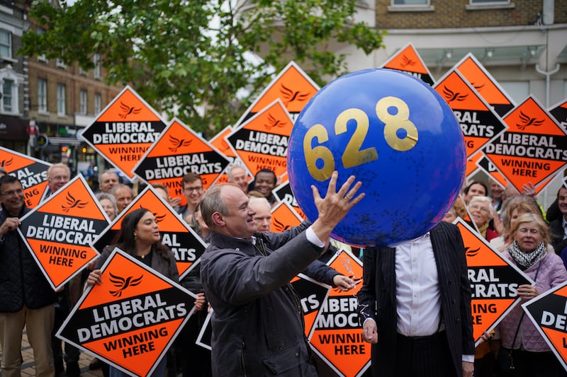 Mr Davey holds a balloon with a figure that represents the amount of votes the Liberal Democrat party lost by in Wimbledon. PA
