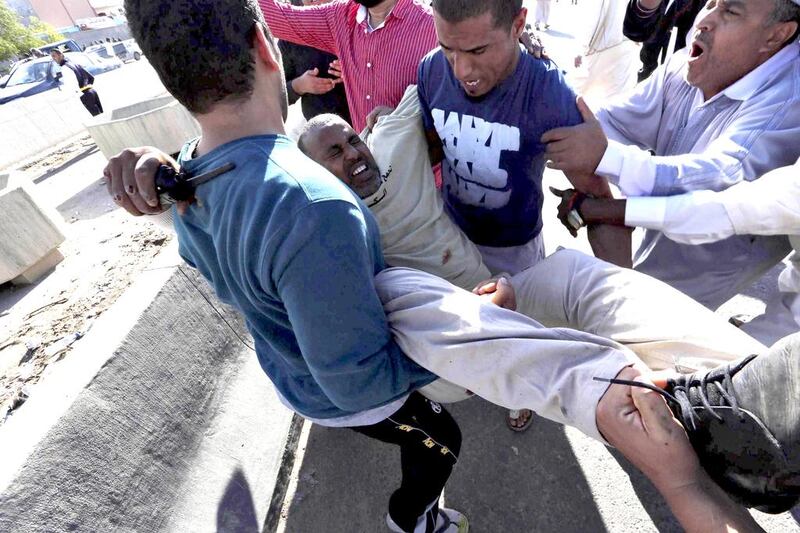 People carry a man who was injured when Libyan militiamen opened fire into a crowd of protesters in Tripoli on Friday. At least four more people were killed on Saturday as fighting in the Libyan capital continued. Reuters 