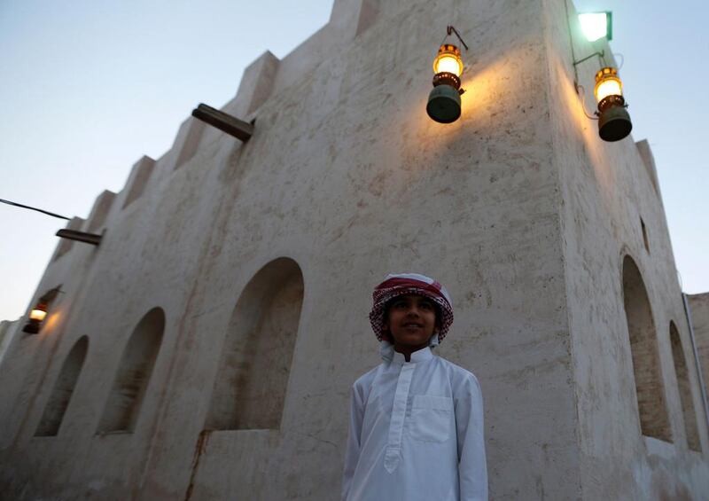 An Emirati boy stands in front of traditional houses.