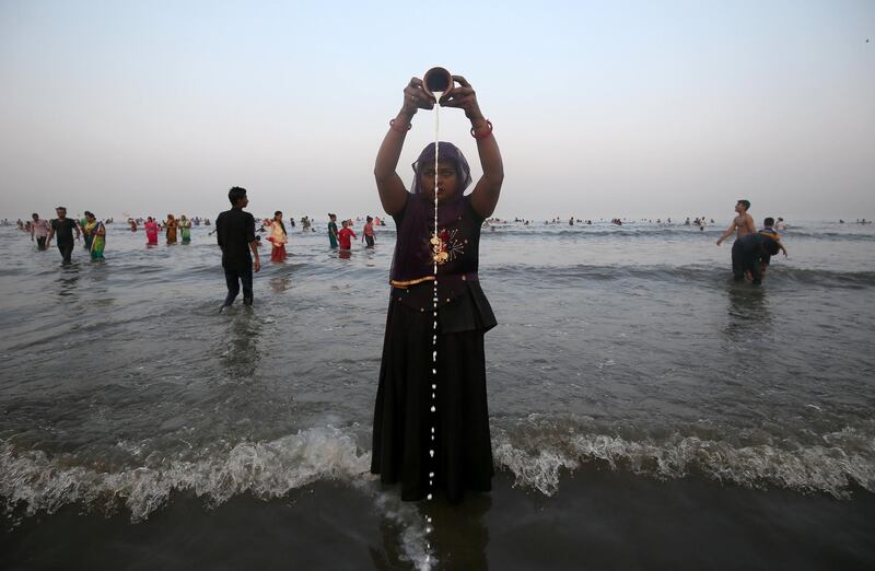A Hindu woman pours milk as she worships the Sun god in the waters of the Arabian Sea in Mumbai. Reuters
