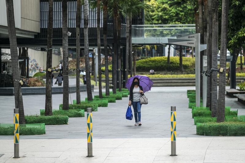 A pedestrian wearing a protective mask walks along a near-deserted road in Bonifacio Global City, Metro Manila. Bloomberg