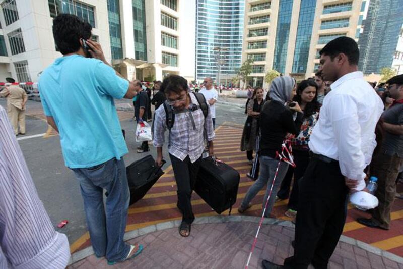 Arun Muralidhar, centre, carries suitcases from his apartment in Tamweel Tower in Jumeirah Lakes Towers in Dubai.