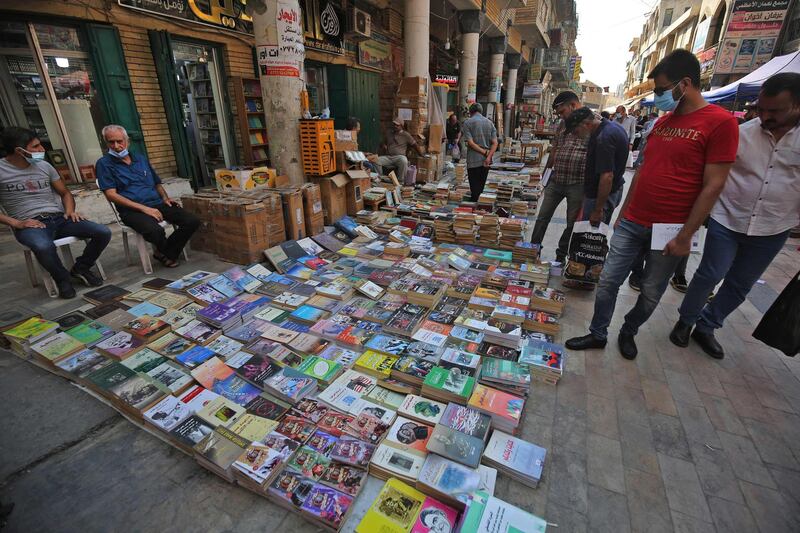 Iraqis wearing face masks check books at a book stall on al-Mutanabi Street in Baghdad. Iraq has been one of the hardest-hit countries in the Middle East by Covid-19, with more than 280,000 infections and nearly 8,000 deaths.  AFP