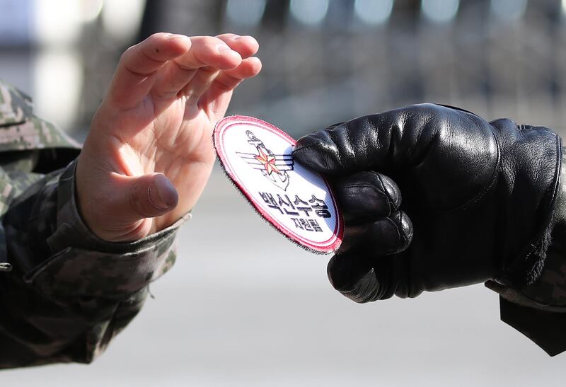 A military officer hands a 'vaccine transportation' patch to a colleague during a joint rehearsal by police and the army for the transportation of COVID-19 vaccines at the National Medical Center in Seoul, South Korea. South Korea will begin its vaccination drive in February.  EPA