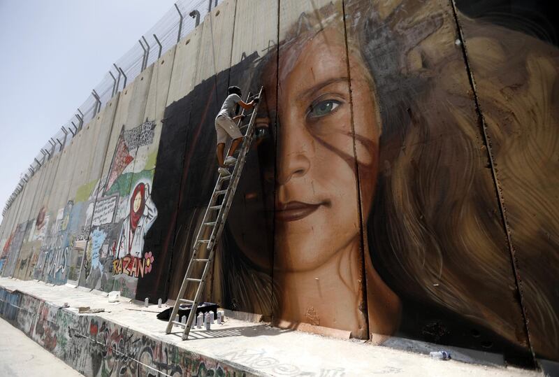 epa06909585 A foreign artist paints a mural of Palestinian Ahed Tamimi on the Israeli separation wall in the West Bank city of Bethlehem, 25 July 2018. Tamimi, 17, is serving an eight-month sentence in Israeli jail and is scheduled to be released on 19 August. Tamimi was arrested on 19 December 2017 by the Israeli army after a video was posted of her slapping Israeli soldiers in the occupied West Bank as they remained impassive.  EPA/ABED AL HASHLAMOUN