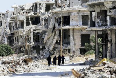 Syrian women walk in between destroyed buildings in the government-held Jouret al-Shiah neighbourhood of the central Syrian city of Homs on September 19, 2016. (Photo by LOUAI BESHARA / AFP)