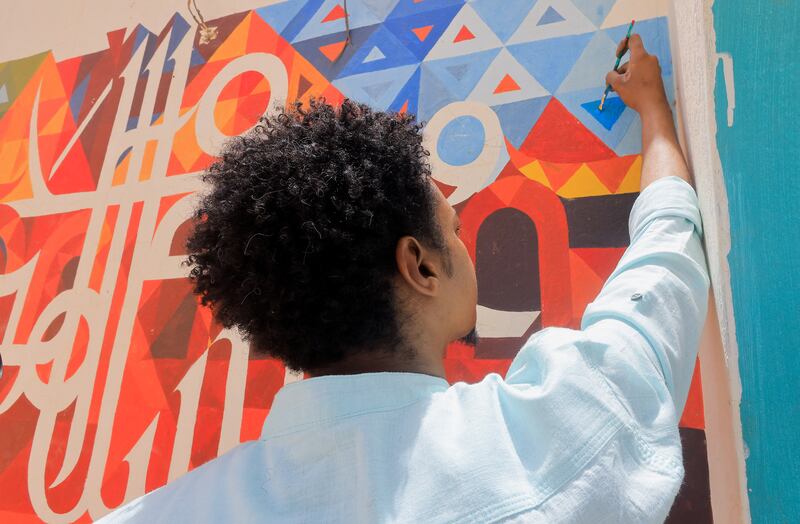 At a primary school in Sudan's capital Omdurman, Ghassan Baloula is working on a mural.