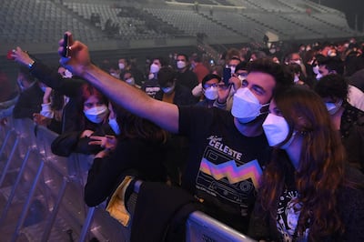 A couple take a selfie as they wait for the start of a rock music concert by Spanish group Love of Lesbian at the Palau Sant Jordi in Barcelona on March 27, 2021.  Attendees underwent Covid-19 Rapid Antigen Tests and are required to wear face masks but the social distancing rule will not be complied as part of a study on virus propagation. / AFP / LLUIS GENE

