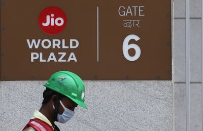 A construction worker walks past a gate of Reliance's Jio World Plaza in Mumbai. Reuters