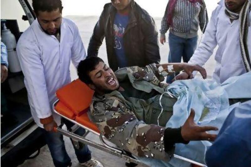 Doctors carry an injured rebel into an ambulance in Brega, Libya, yesterday. Many rebels were angry at international inaction.
