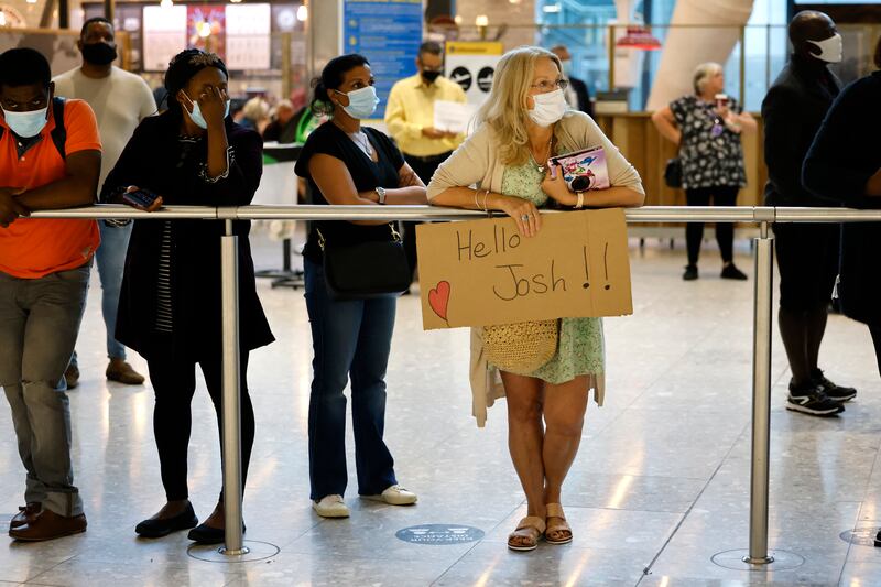A mother holds a sign for her son as she waits for him at Terminal 5. AFP