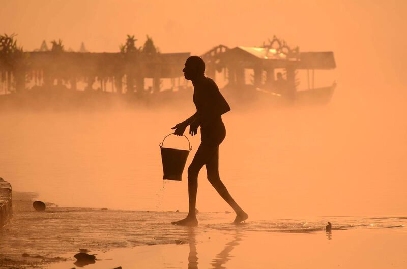 A Hindu devotee carries a bucket of water from Narmada river in Jabalpur in Madhya Pradesh state, India. AFP