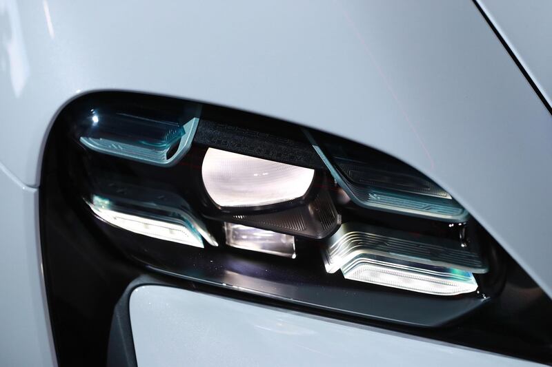 An illuminated headlight sits on the all-electric Porsche AG Taycan luxury automobile. Bloomberg