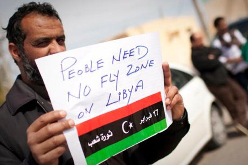 A Libyan man holds up a sign asking for a no-fly zone over Libya near the border town of Musa'id, Libya, Sunday, March 13, 2011. Moammar Gadhafi's forces swept rebels from one of their final strongholds on Libya's  main coastal highway on Sunday, closing on the country's opposition-held eastern half after hours of searing waves of strikes from warships, tanks and warplanes. (AP Photo/Anja Niedringhaus) *** Local Caption ***  ANS103_Mideast_Libya.jpg