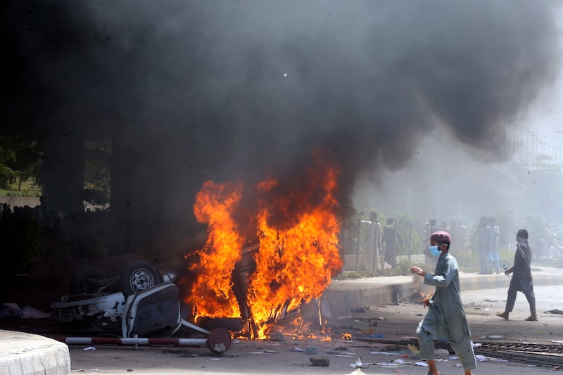 A car set on fire in Peshawar by supporters of Mr Khan during a protest. AP