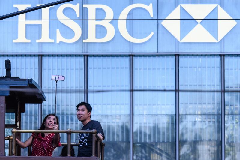 Tourists pose for a selfie as they stand on the top deck of a tram while passing the local HSBC headquarters building in Hong Kong on October 29, 2018. HSBC saw profits up 28percent at 5.9 billion USD in the third quarter.  / AFP / Anthony WALLACE
