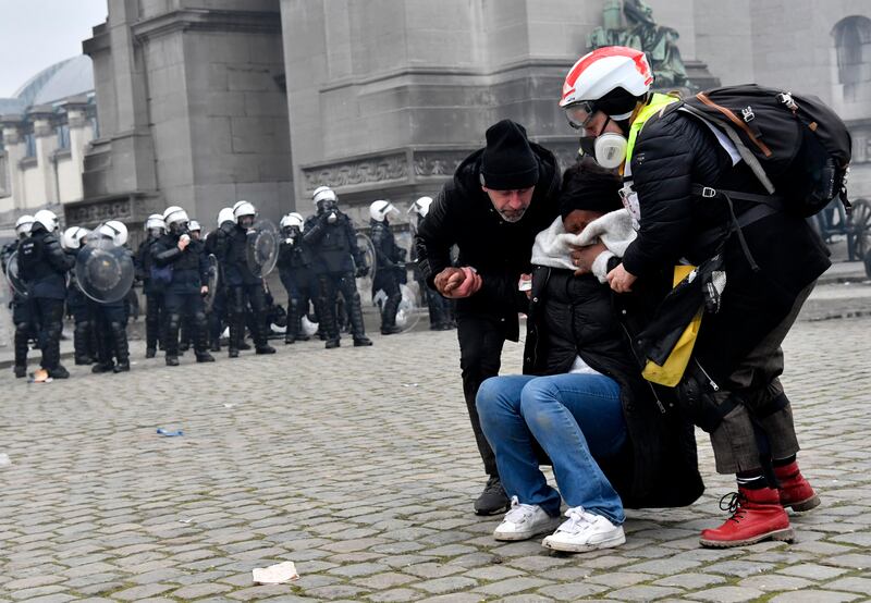 Two people help a woman overcome by tear gas during a mass demonstration against Covid-19 measures in the Belgian capital Brussels. AP