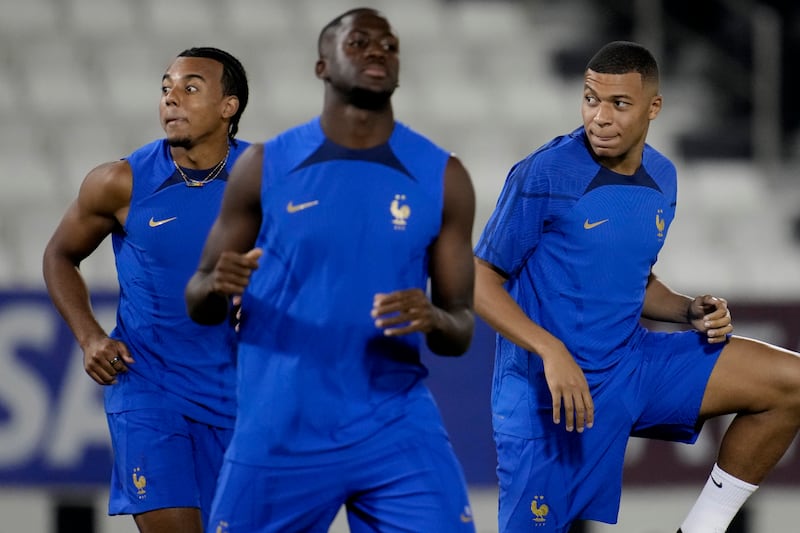 Jules Kounde and Kylian Mbappe stretch during a training session. AP