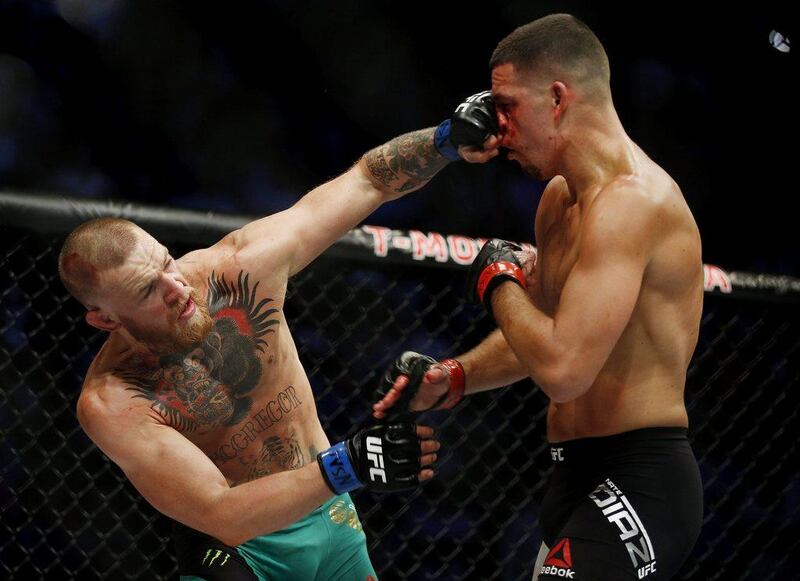 Conor McGregor punches Nate Diaz during their welterweight bout at UFC 202 on August 20, 2016, in Las Vegas.